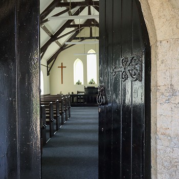 black wooden door half open into the church